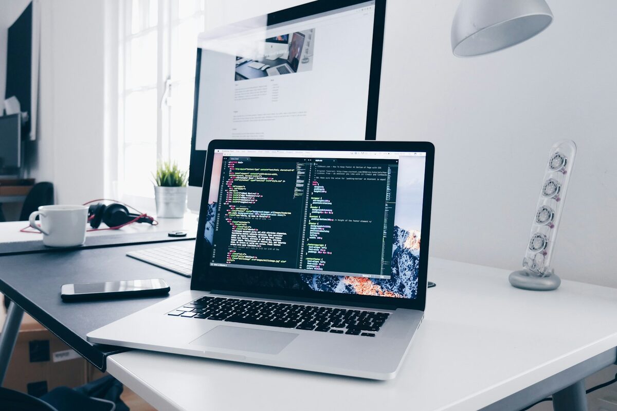 Laptop di atas meja kerja dengan kabel dan perlengkapan, suasana calon pembeli mengecek unit bekas (kredit: unsplash.com)