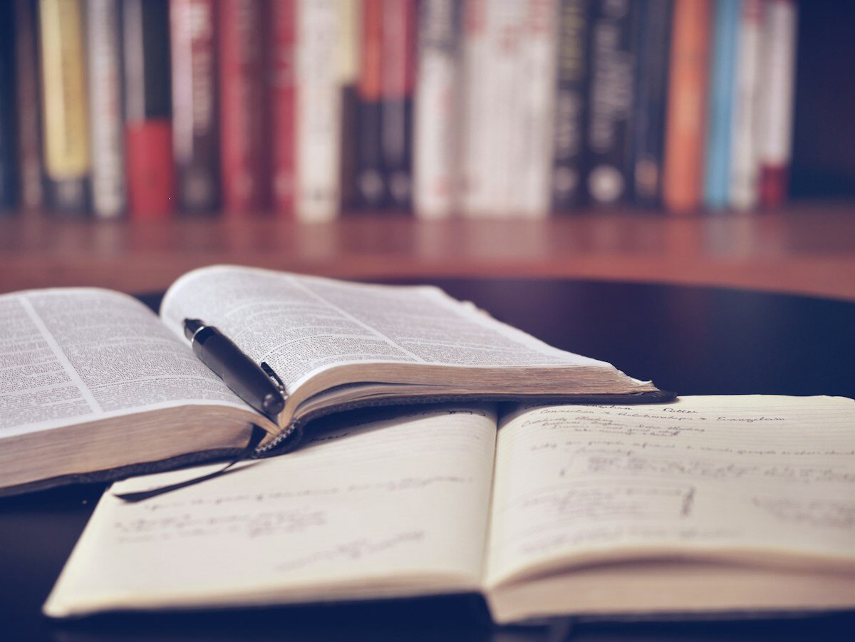 Meja belajar dengan buku terbuka dan cahaya hangat, suasana belajar sendirian di malam hari (kredit: unsplash.com)